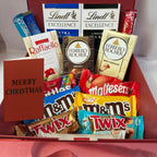 Assorted chocolate bars including Twix, Maltesers, and Ferrero Rocher in a box with a 'Merry Christmas' card.