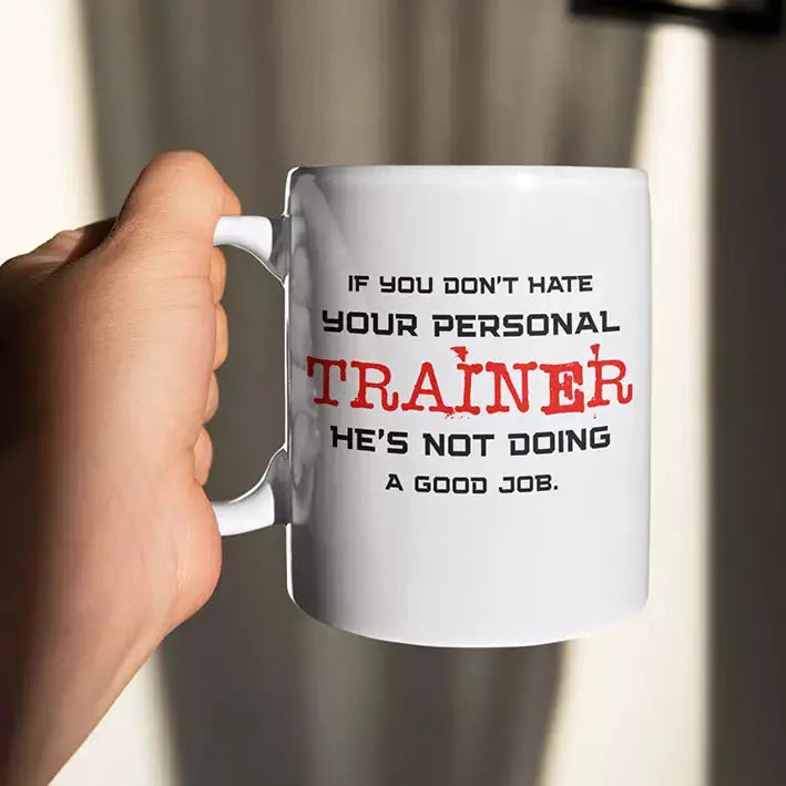 White ceramic personalised gym mug featuring the quote “If You Don't Hate Your Personal Trainer He's Not Doing a Good Job” on the front.