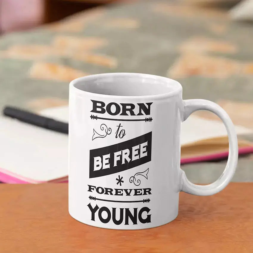 Born to Be Free Forever Young ceramic mug with black interior and quote design.