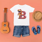 White t-shirt with dinosaur design, denim shorts, ukulele, straw hat, and blue flip-flops on a peach background