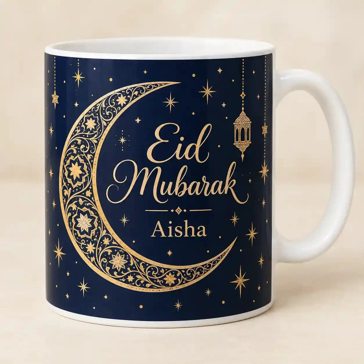 Personalised Eid Mubarak mug with gold crescent moon, stars and lantern on a navy-blue background, featuring the custom name Aisha.