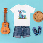 White t-shirt with dinosaur graphic, denim shorts, ukulele, straw hat, and flip-flops on a blue background