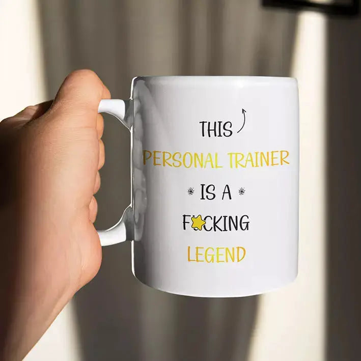 Personalised white ceramic mug printed with the bold “This Personal Trainer Is A F*cking Legend” slogan, a funny thank-you gift for a fitness coach.