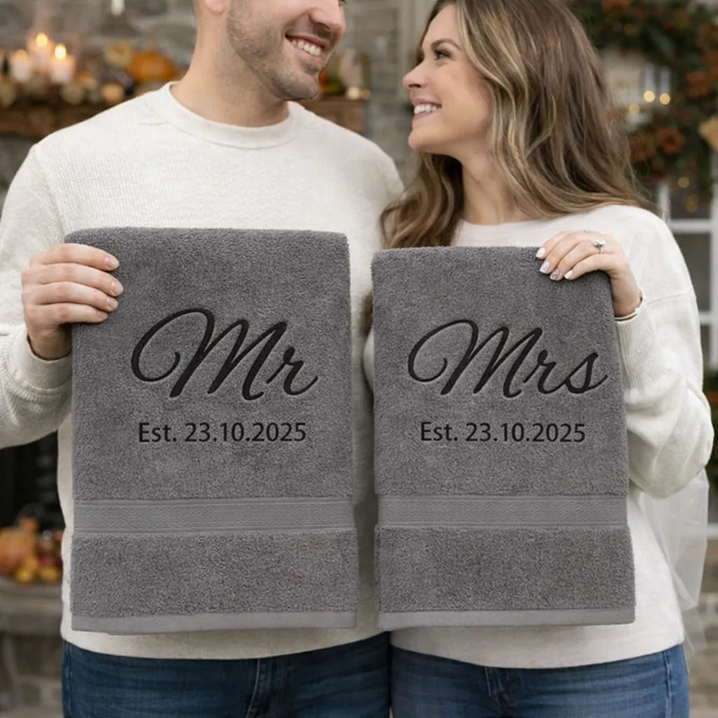 Couple holding personalised Mr and Mrs anniversary towels with embroidered establishment date
