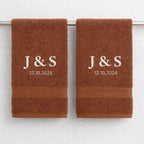 Personalised couple towels embroidered with initials and engagement date hanging in bathroom