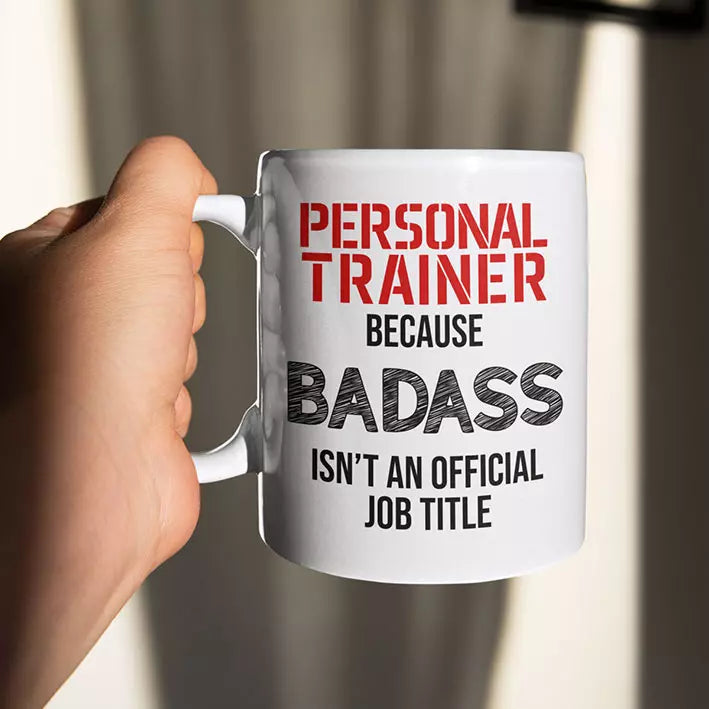 White personalised ceramic mug featuring the funny “Personal Trainer Because Badass Isn't an Official Job Title” quote, with optional name or message on reverse.