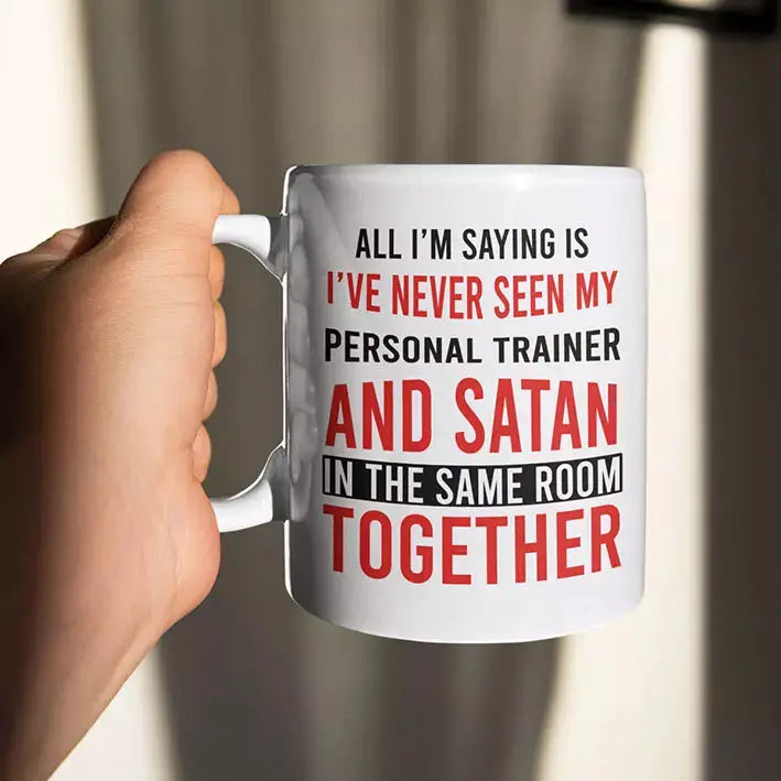 Ceramic personal trainer mug printed with the joke about never seeing a personal trainer and Satan in the same room, with reverse personalisation available.