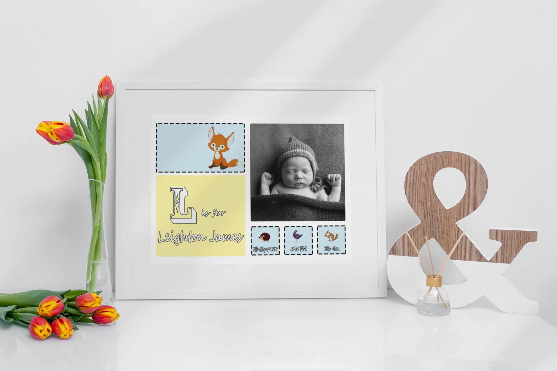 “Personalised new baby photo frame with infant picture, custom name, initial, birth details, and cute animal illustrations displayed on a white tabletop with tulips.”