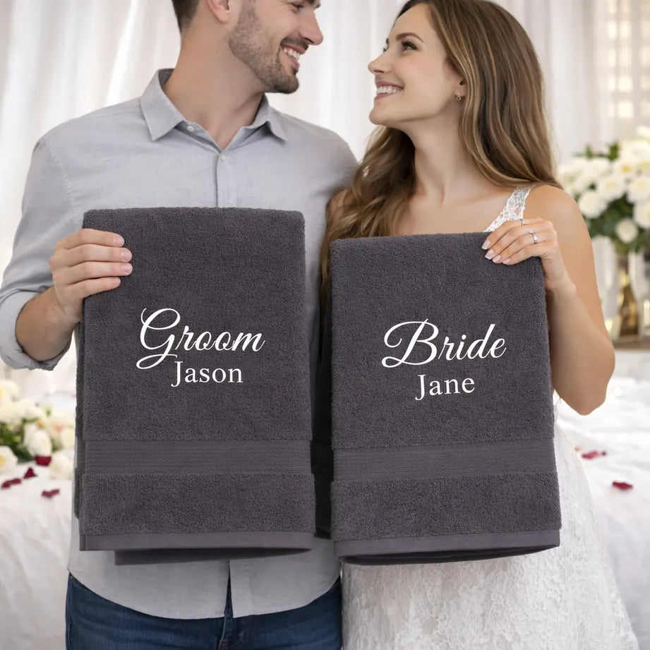 Newlywed couple holding personalised Bride and Groom towels with embroidered names in wedding setting
